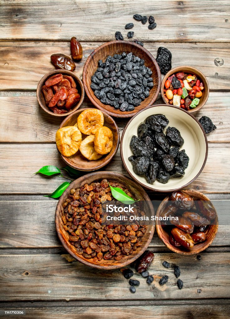 Assortment of different dried fruits in bowls. On a Wooden background.